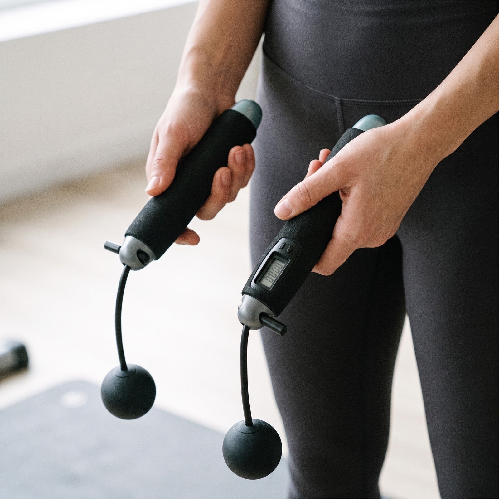 Hands gripping Black handles with short cords and weighted balls