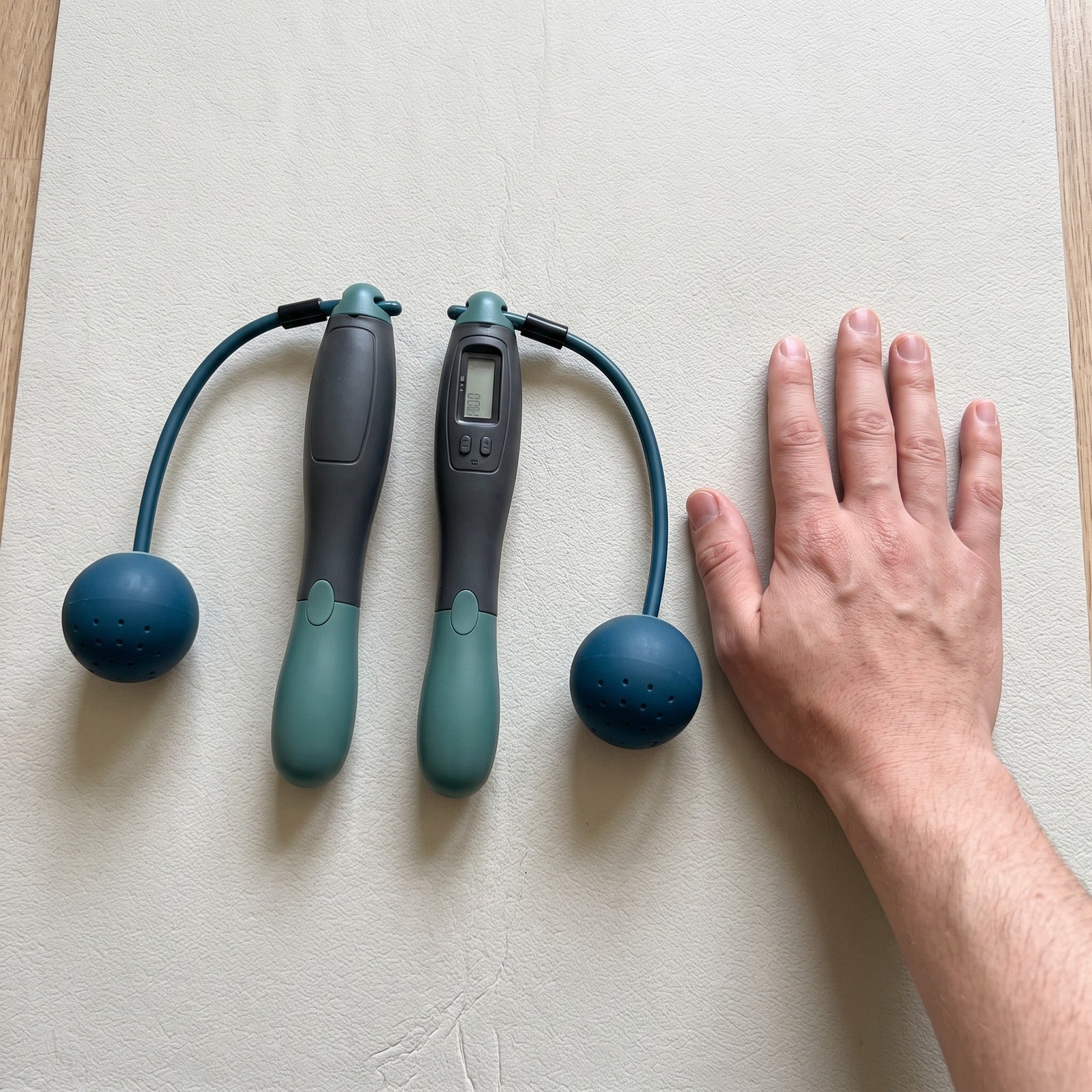 Green rope set beside a hand on a workout mat